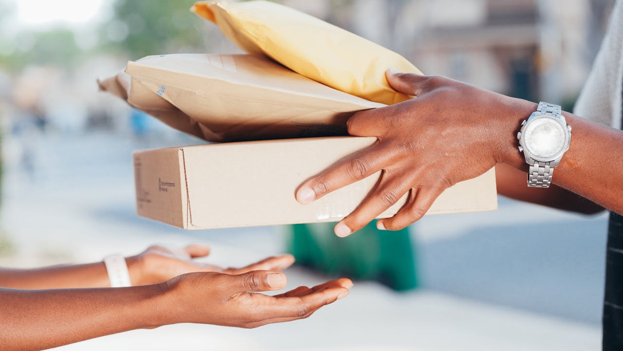 our-mission Close-up image of hands exchanging packages outdoors. Represents delivery and shipping services.